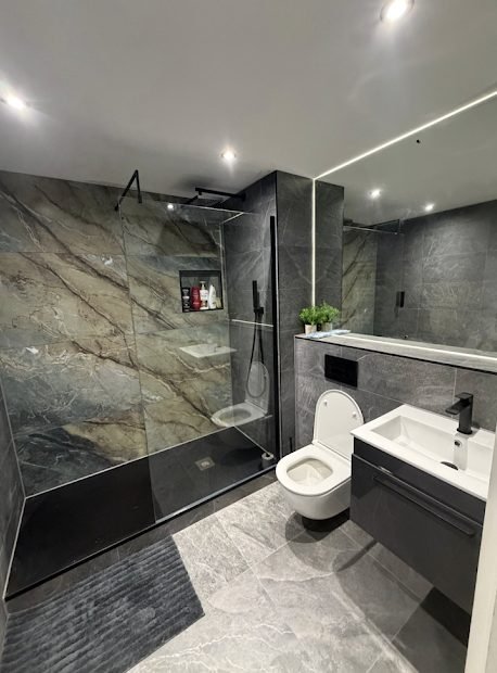 Dark grey marble wet room with level access shower and wall hung WC
